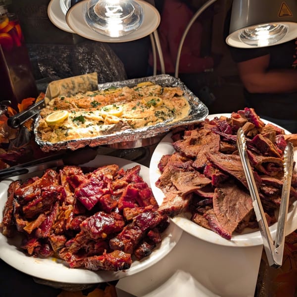 Buffet spread with baked fish, BBQ ribs, and sliced brisket under heat lamps.